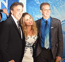 三個人在《冰雪奇緣》主題紅毯背景前微笑拍照