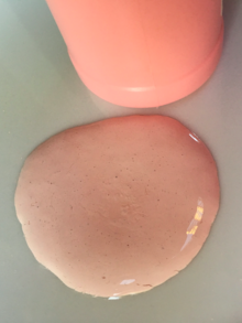 一滩粉红色的薄乳液，旁边是一个粉红色的塑料瓶