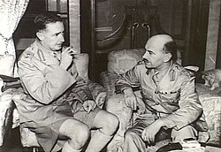 罗逊准将（图中右方）与莫德庇少将正在讨论香港防务。罗逊随加拿大援军于1941年11月16日抵达香港，莫德庇于12月12日决定将“港岛旅”分为“东旅”及“西旅”后，罗逊负责指挥香港岛的西旅部队，而从新界及九龙撤到港岛的原“大陆旅”指挥官华里士准将则负责指挥东旅部队。罗逊准将于12月19日在黄泥涌峡带领部下从被日军包围的西旅指挥部突围时战死。