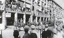 1941年12月28日，日军先后在九龙及香港岛举行入城式，陆军第23军司令酒井隆（左二）及海军第二遣支舰队司令新见政一（左一）在轩尼诗道策马检阅侵港日军，并向在路旁列队的日军士兵敬礼。