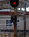 車站構內的高架電纜電源識別標識，白色縱二燈顯示直流通電中。