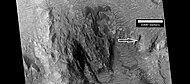 高分辨率成像科学设备显示的奥基陨击坑中部，箭头指示了脊线位置，沙丘出现在图像顶部附近。