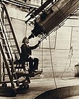 一个人坐在安装一个移动的平台的椅子，通过大型望远镜观测。